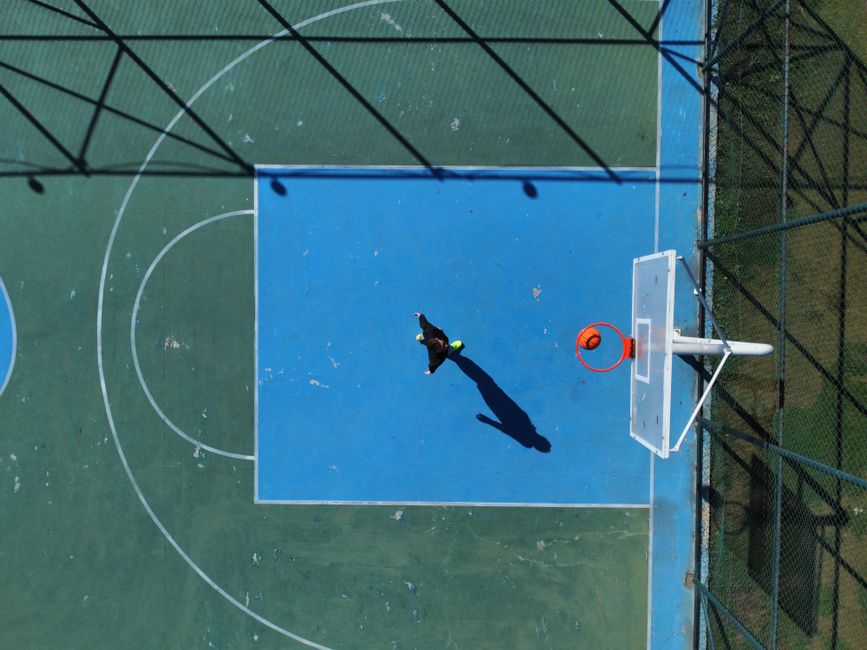 Drone shot capturing a person on a basketball court, showcasing athletic movement from an aerial perspective.