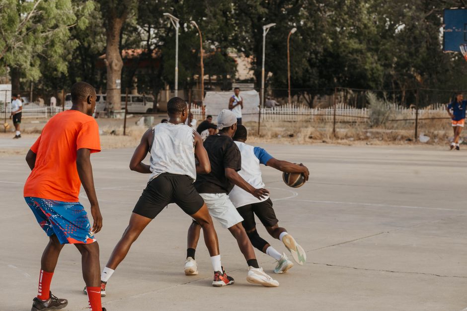 Group of young men playing basketball on an outdoor court in a lively match.