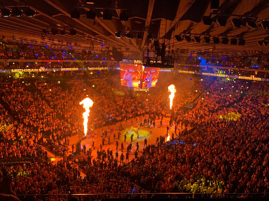 Crowd of people sitting on tribunes of spacious stage and watching performance with torches while celebrating game in modern sport place