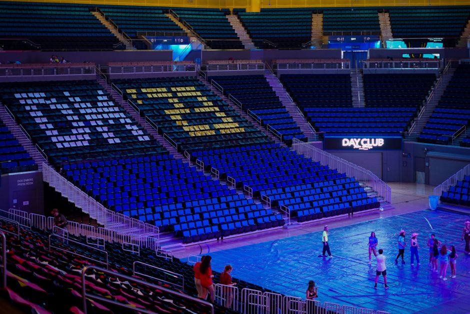 Interior view of Pauley Pavilion, Los Angeles, with empty colorful seats and few people on court.