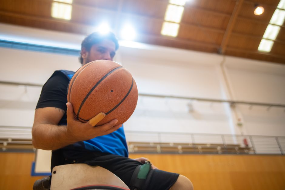 Focused view of a wheelchair basketball player holding a ball in an indoor court setting.