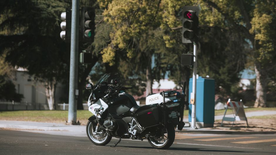 A police motorcycle stopped at a city intersection with traffic lights.